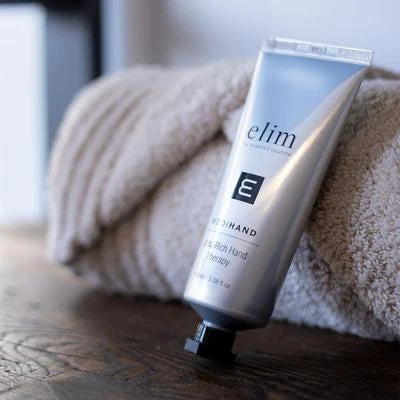 Elim MediHand Nail Care cream tube on a soft towel, designed for aging and pigmented hands protection.