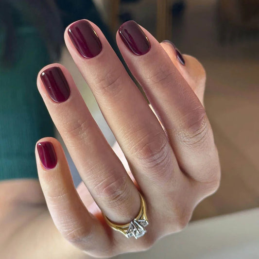 Hand with light skin tone wearing Bio Sculpture Gemini Nail Polish No. 10 Pinotage – vegan, wine brown polish with grape undertone for a chic, sophisticated nail look