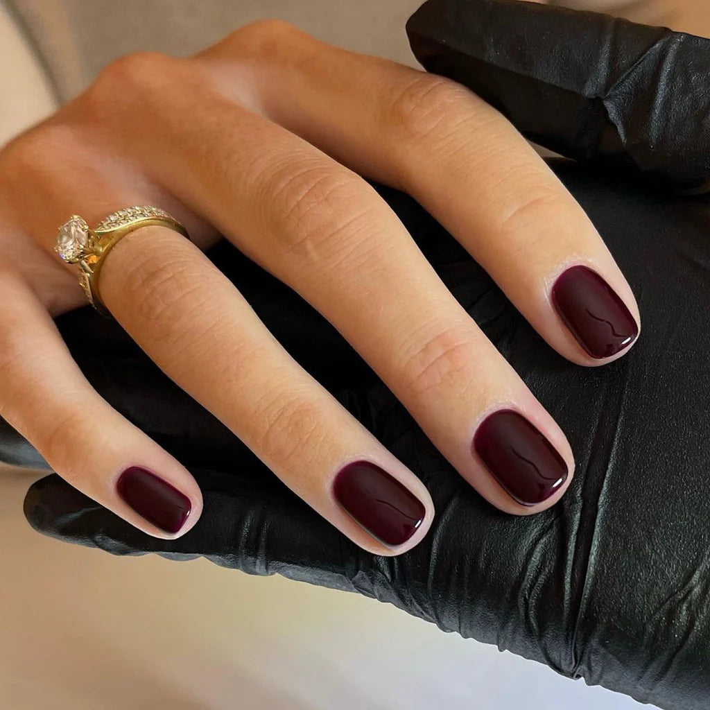 Hand wearing Bio Sculpture Gemini Nail Polish No. 10 Pinotage – bold, vegan wine brown polish with grape undertone for inclusive, striking manicures