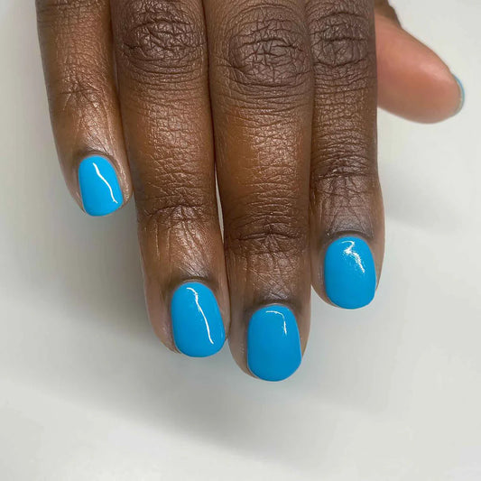 Close-up of Bio Sculpture Gemini Nail Polish No. 134 Aquacade polish on dark skin – eco-friendly, vibrant aqua blue shade for glowing, beautiful nails