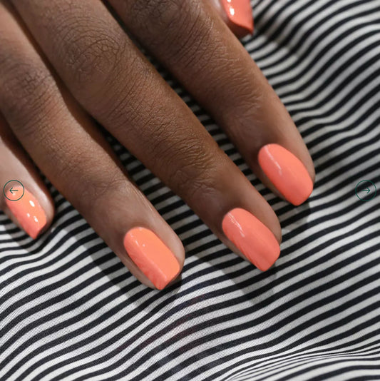 Hand with dark skin tone wearing Manucurist Bird of Paradise – bright, eco-friendly orange polish for inclusive, striking nail looks