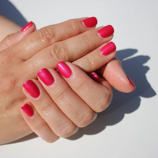 Hand wearing Bio Sculpture Gemini Nail Polish No. 109 Berry Medley – vegan, deep raspberry pink polish with a pearlescent finish for a chic, radiant nail look
