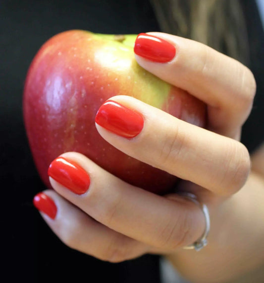 Hand wearing Bio Sculpture Gemini Nail Polish No. 117 Breaking Dawn – vegan, shimmery bright red polish for a glamorous, eye-catching nail look