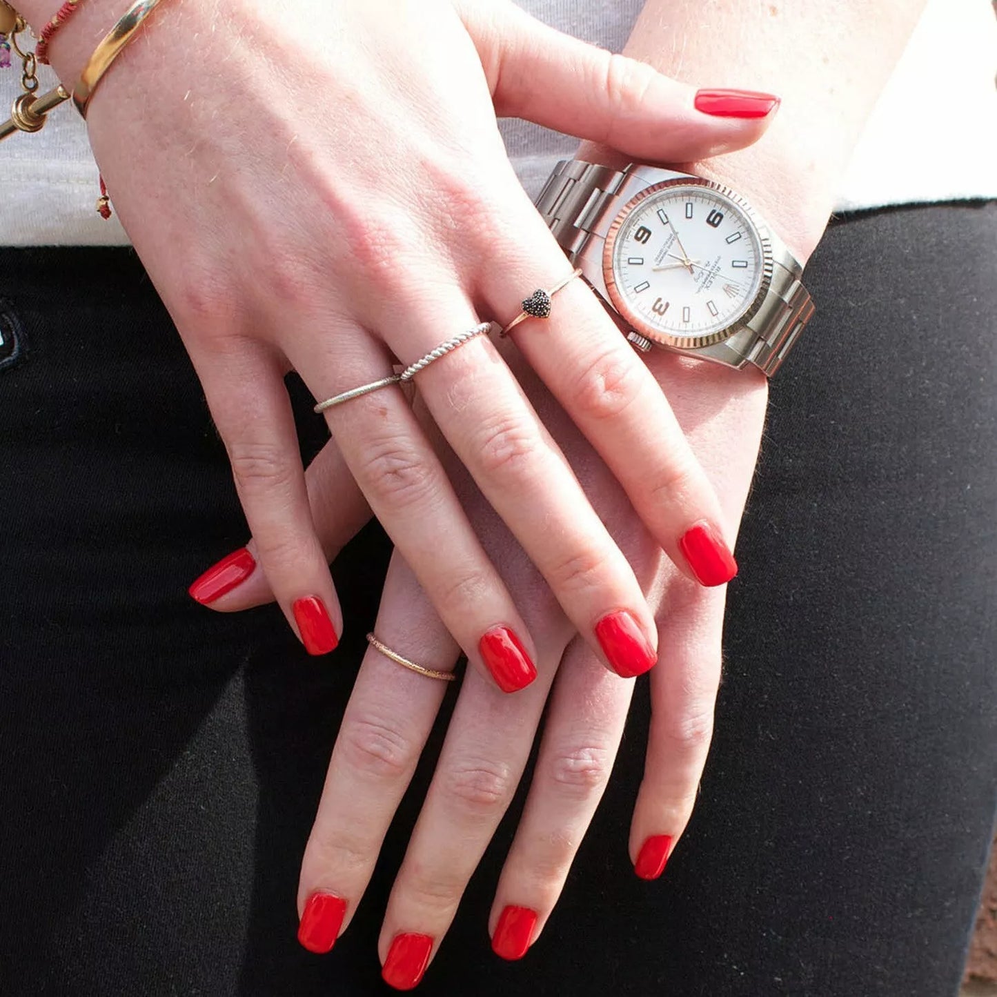 Hand with dark skin tone wearing Bio Sculpture Blazing Lacquer – bold, vegan bright orange-red polish for inclusive, striking manicures