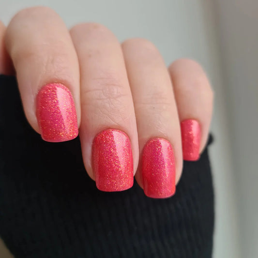 Hand with light skin tone wearing Bio Sculpture Gemini Nail Polish No. 214 Bring Out The Beauty – vegan, pink glitter polish for a dazzling, eye-catching nail look