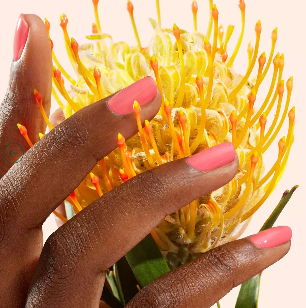 Hand with darker skin tone wearing Manucurist Capucine – vivid, eco-friendly orange polish for striking, inclusive nail looks