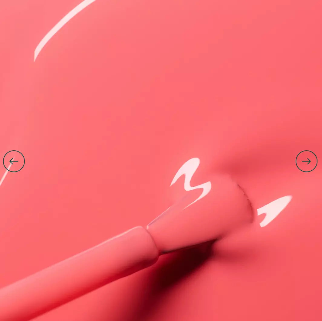 Polish brush dipped in Manucurist Capucine nail polish – creamy, non-toxic orange formula for smooth application