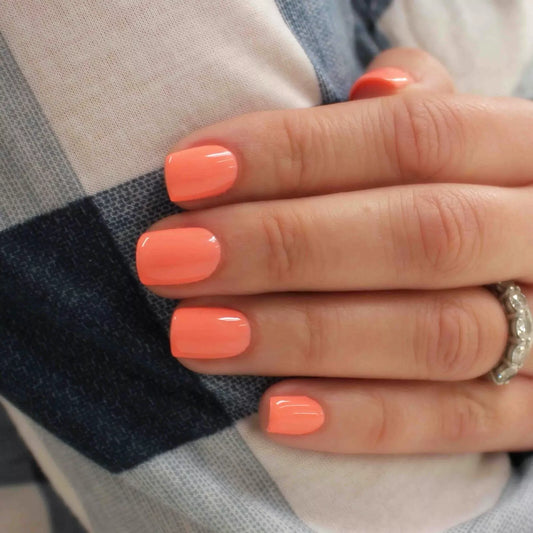 Hand with light skin tone wearing Bio Sculpture Gemini Nail Polish No. 249 Coral Cluster – vegan, bright coral polish for a vibrant, cheerful nail look