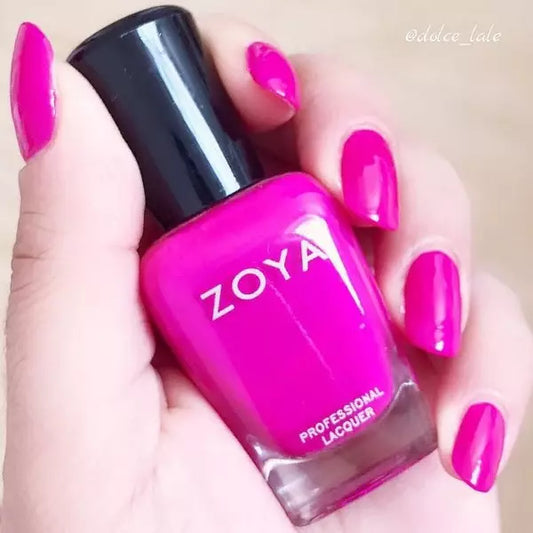 Hand holding Zoya Charisma nail polish – vibrant neon magenta purple shade for striking, modern nail looks