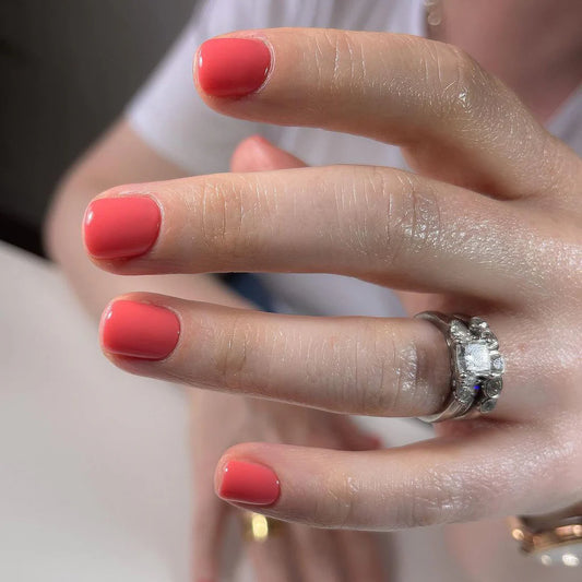 Hand with light skin tone wearing Bio Sculpture Gemini Nail Polish No. 132 Coral Cove – vegan, peachy coral polish for a chic, radiant nail look
