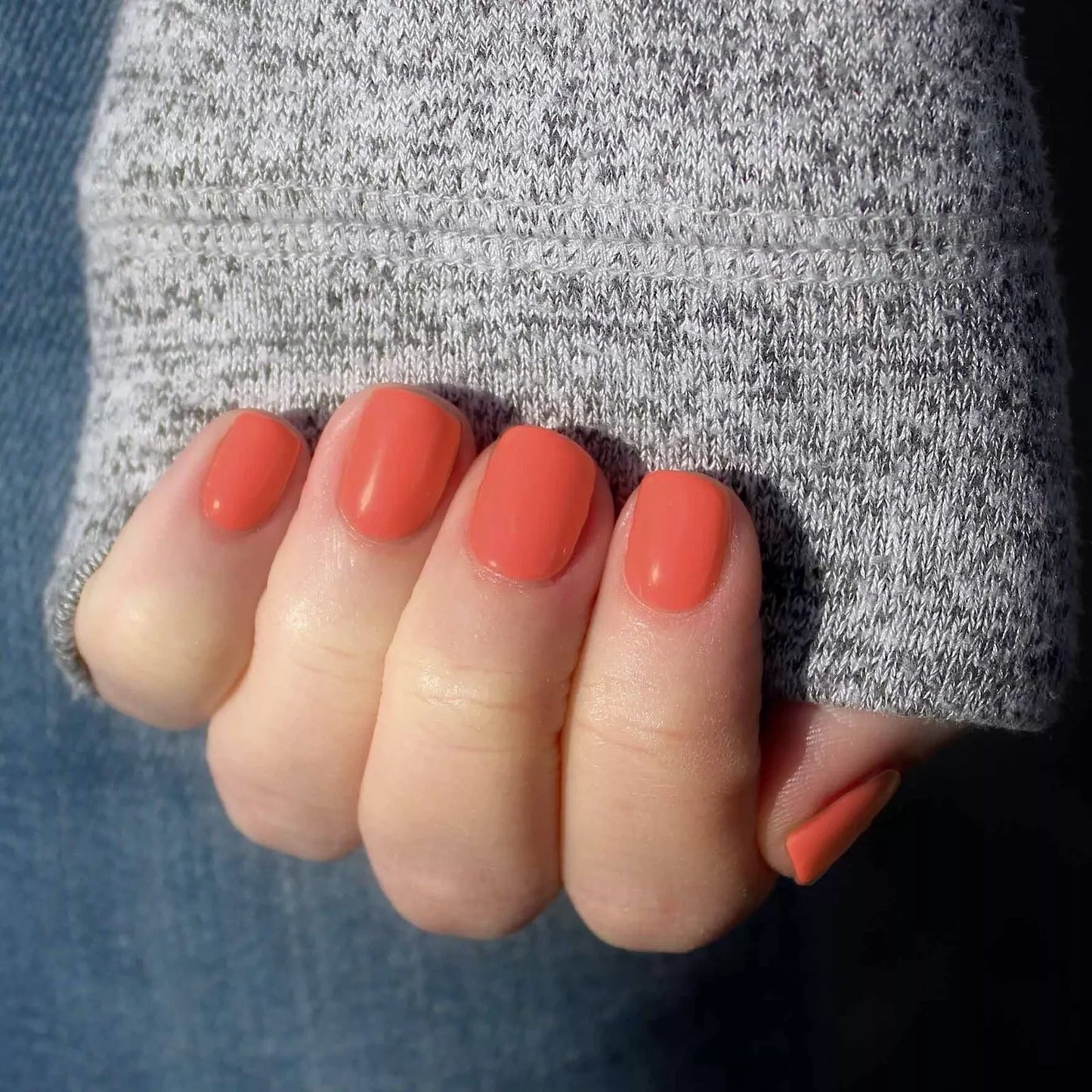 Hand wearing Bio Sculpture Gemini Nail Polish No. 132 Coral Cove – bold, vegan peachy coral polish for inclusive, glowing manicures