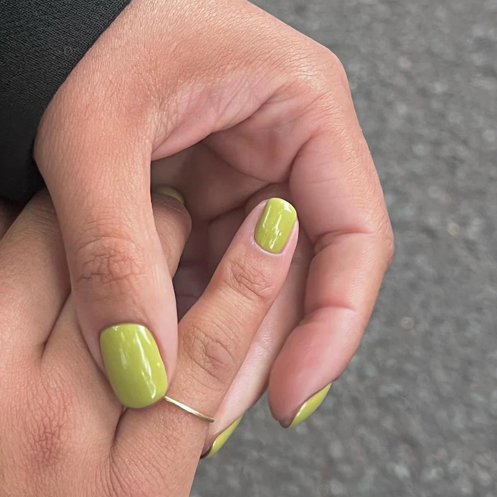 Fingers painted with Gemini Feel the Veld on light skin – breathable, earthy green polish for everyday elegance