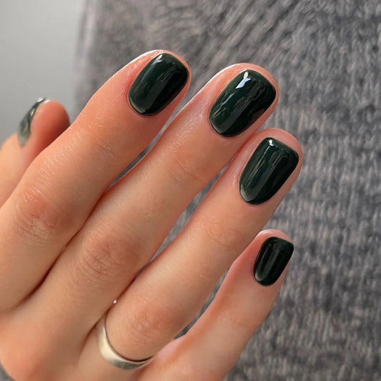 Hand with light skin tone wearing Bio Sculpture Gemini Nail Polish No. 183 Free Lovin – vegan, dark bottle green polish inspired by Lydia Millin Evergreen for a chic, elegant nail look