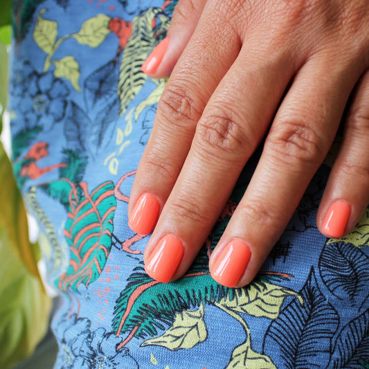 Hand with light skin tone wearing Bio Sculpture Gemini Nail Polish No. 196 Free Spirit – vegan, fluorescent coral polish for a lively, eye-catching nail look