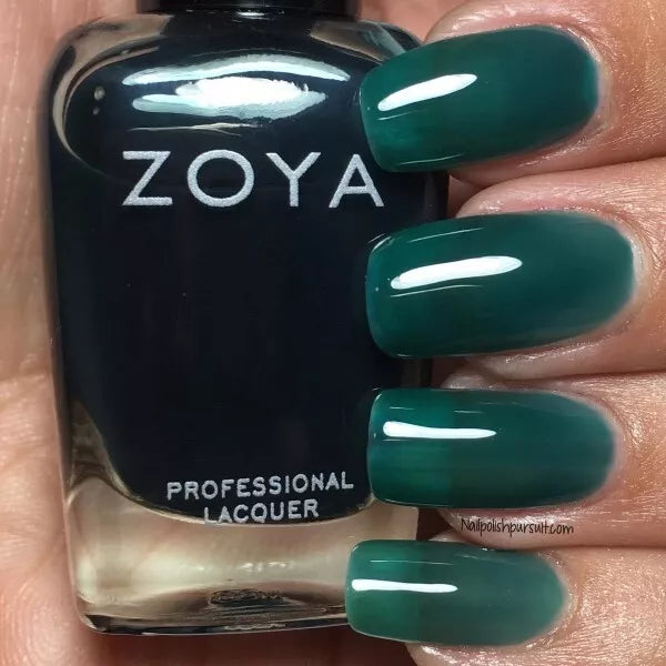 Hand with Zoya Frida nail polish bottle – translucent teal blue polish for a chic, elegant nail look