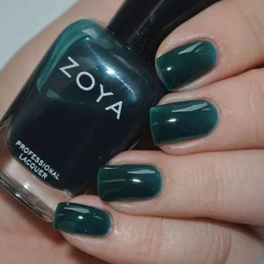 Hand holding Zoya Frida nail polish – vegan, sheer teal blue polish bottle for stylish, modern manicures