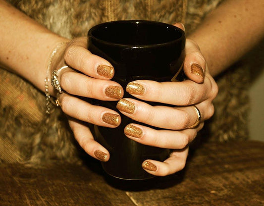 Fingers painted with Bio Sculpture Gemini Nail Polish No. 291 Golden Fall on light skin – breathable, bold gold glitter polish for a polished, festive style