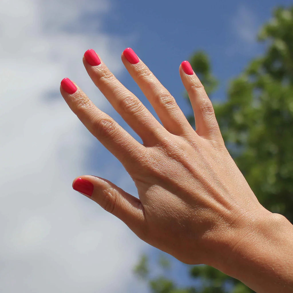 Hand with dark skin tone wearing Bio Sculpture Gemini Nail Polish No. 173 Ipanema Sunset – bold, vegan hot pink polish for inclusive, striking manicures