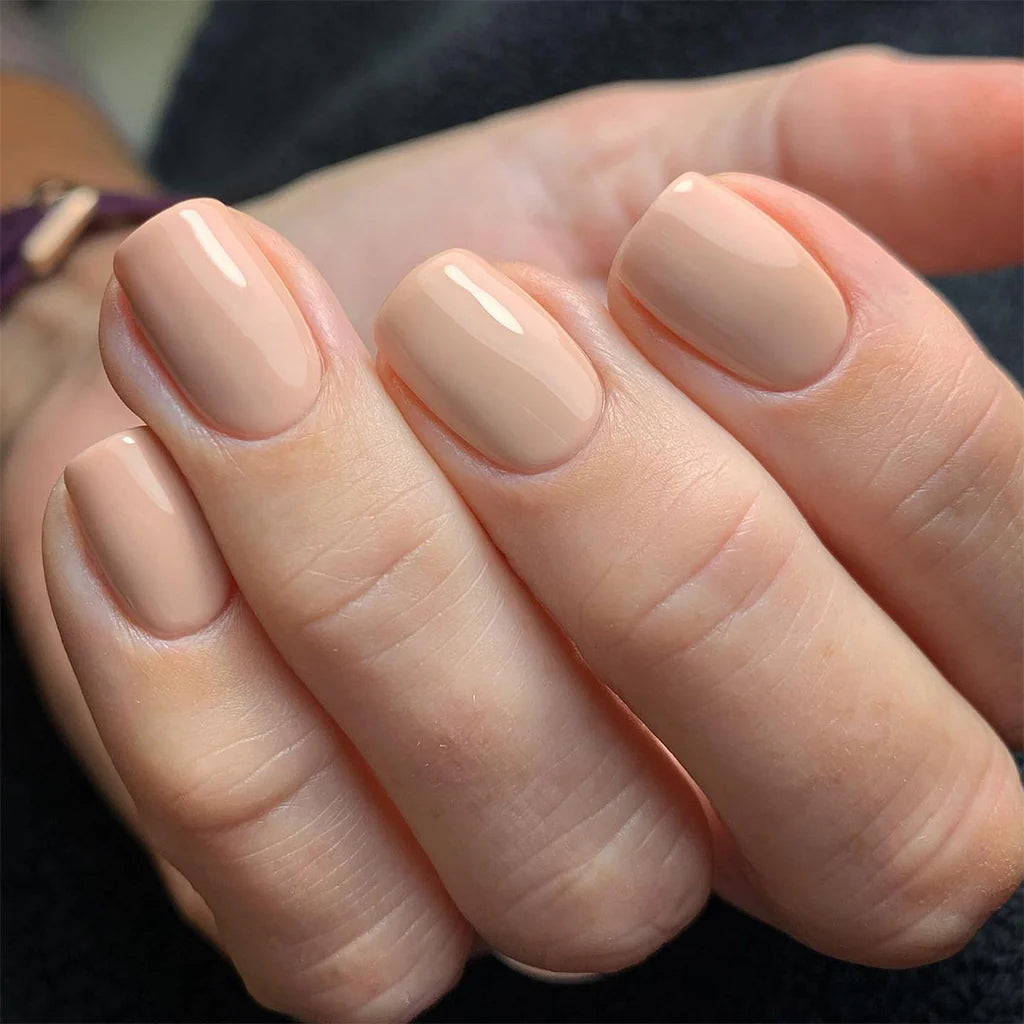 Hand wearing Bio Sculpture Gemini Nail Polish No. 2093 Ivory Beige – vegan, translucent peachy nude polish for a chic, understated nail look