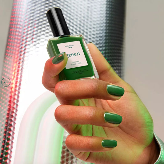 Hand holding Manucurist Paris Green Range Jade – vibrant, plant-based jade green nail polish bottle