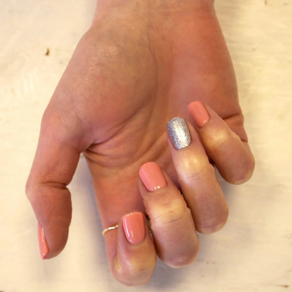Hand wearing Bio Sculpture Gemini Nail Polish No. 155 Jackie – vegan, peach coral polish for a chic, vibrant nail look