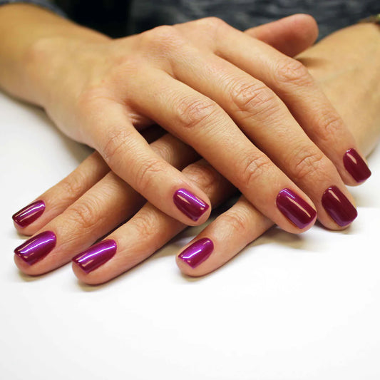 Hand wearing Bio Sculpture Gemini Nail Polish No. 2018 Plum Passion – vegan, pearlescent raspberry polish with a purple undertone for a chic, radiant nail look