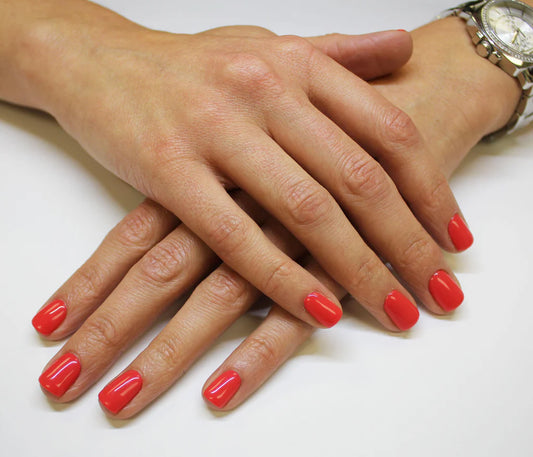 Hand wearing Bio Sculpture Gemini Nail Polish No. 216 Violently Happy – vegan, vibrant coral polish for a chic, radiant nail look