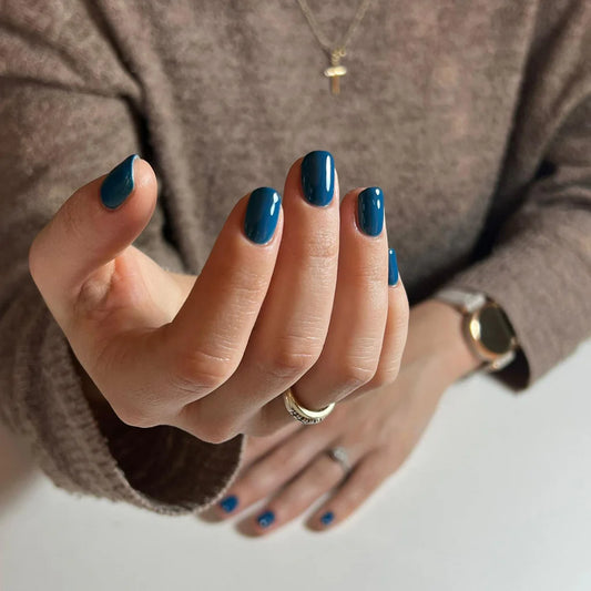 Hand wearing Bio Sculpture Gemini Nail Polish No. 234 Elegance – vegan, deep teal blue polish for a chic, elegant nail look