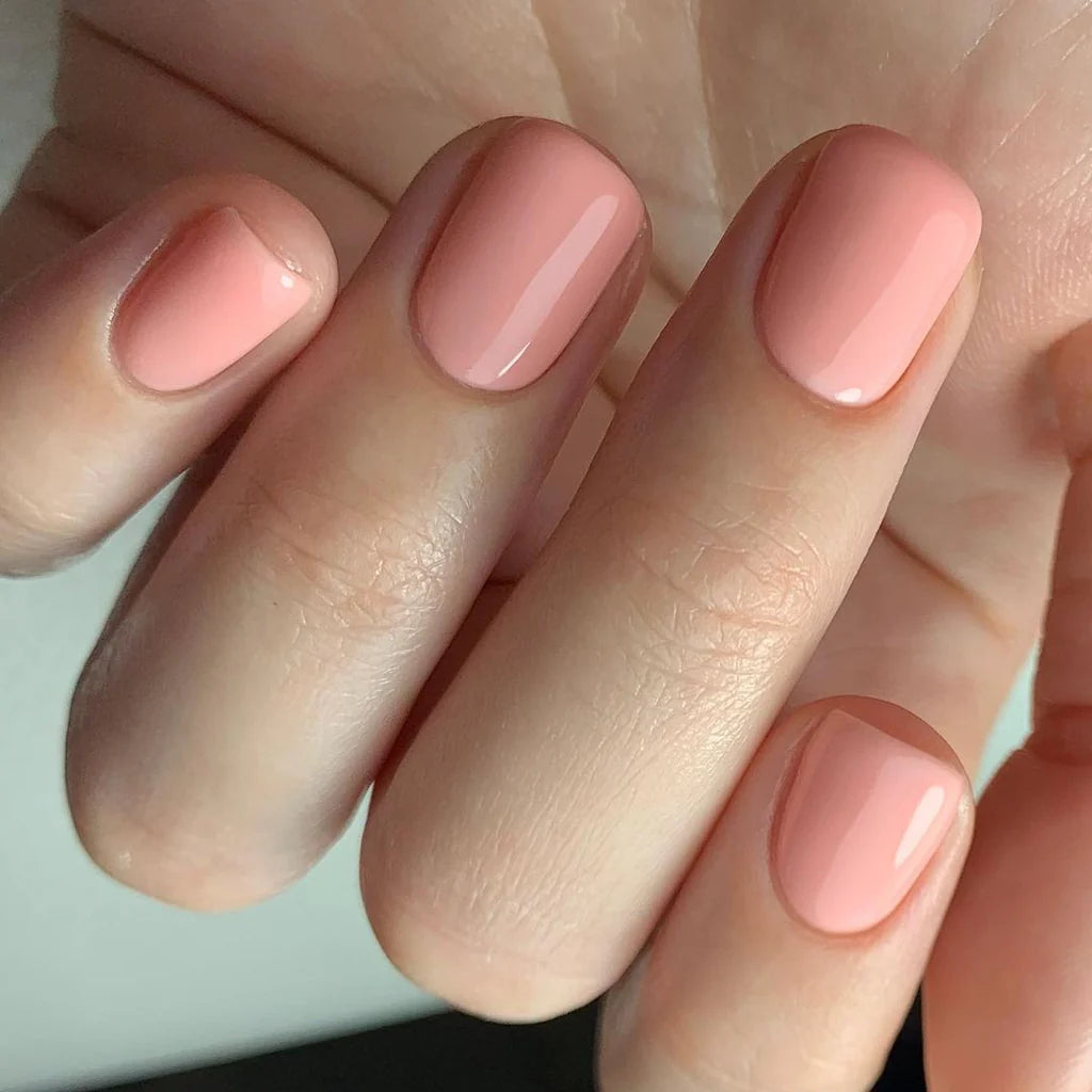 Hand wearing Bio Sculpture Gemini Nail Polish No. 246 Island Surf – bold, vegan creamy pastel coral polish for inclusive, radiant manicures