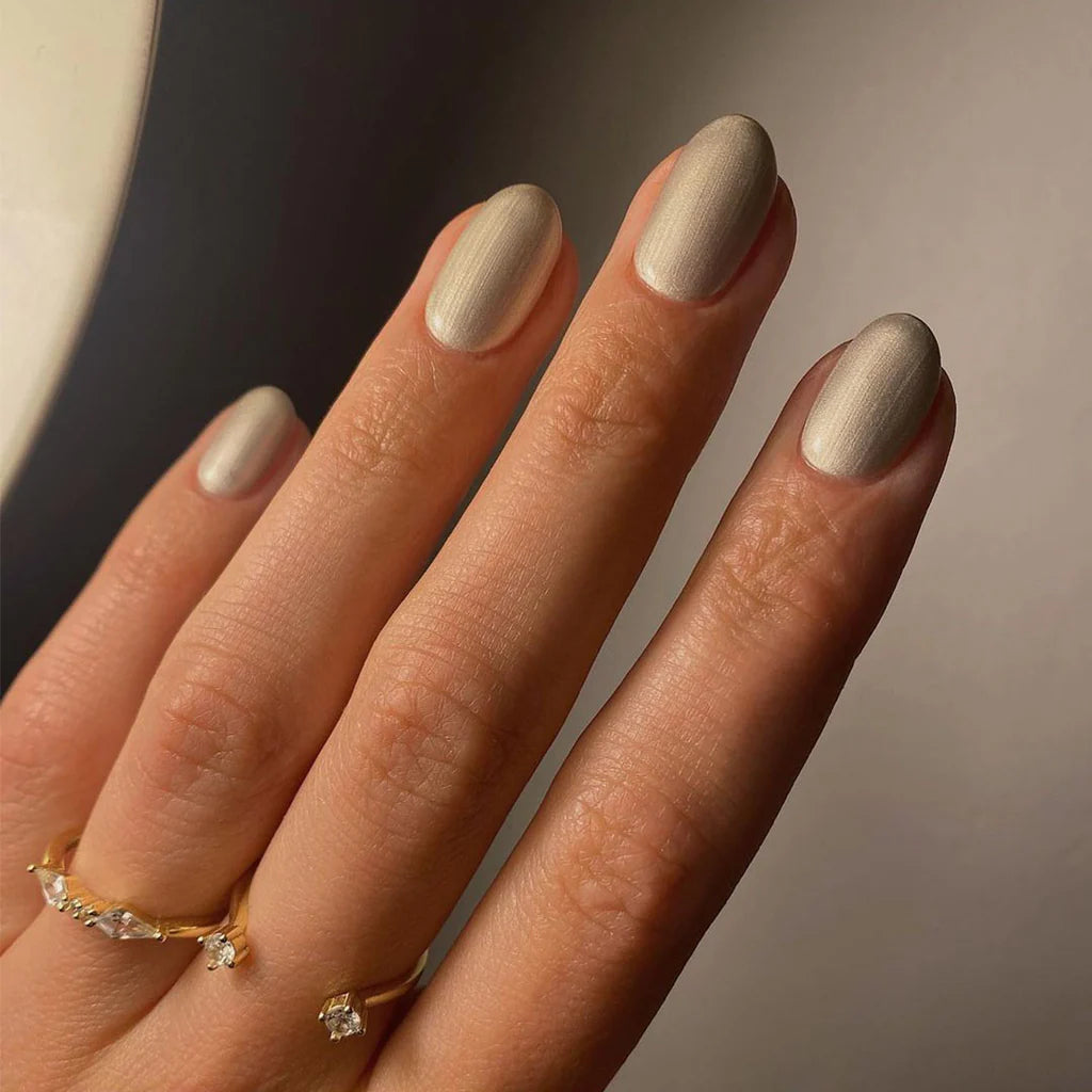 Hand with light skin tone wearing Bio Sculpture Gemini Nail Polish No. 251 Angelic Statue – vegan, pearlescent champagne polish for a chic, luminous nail look