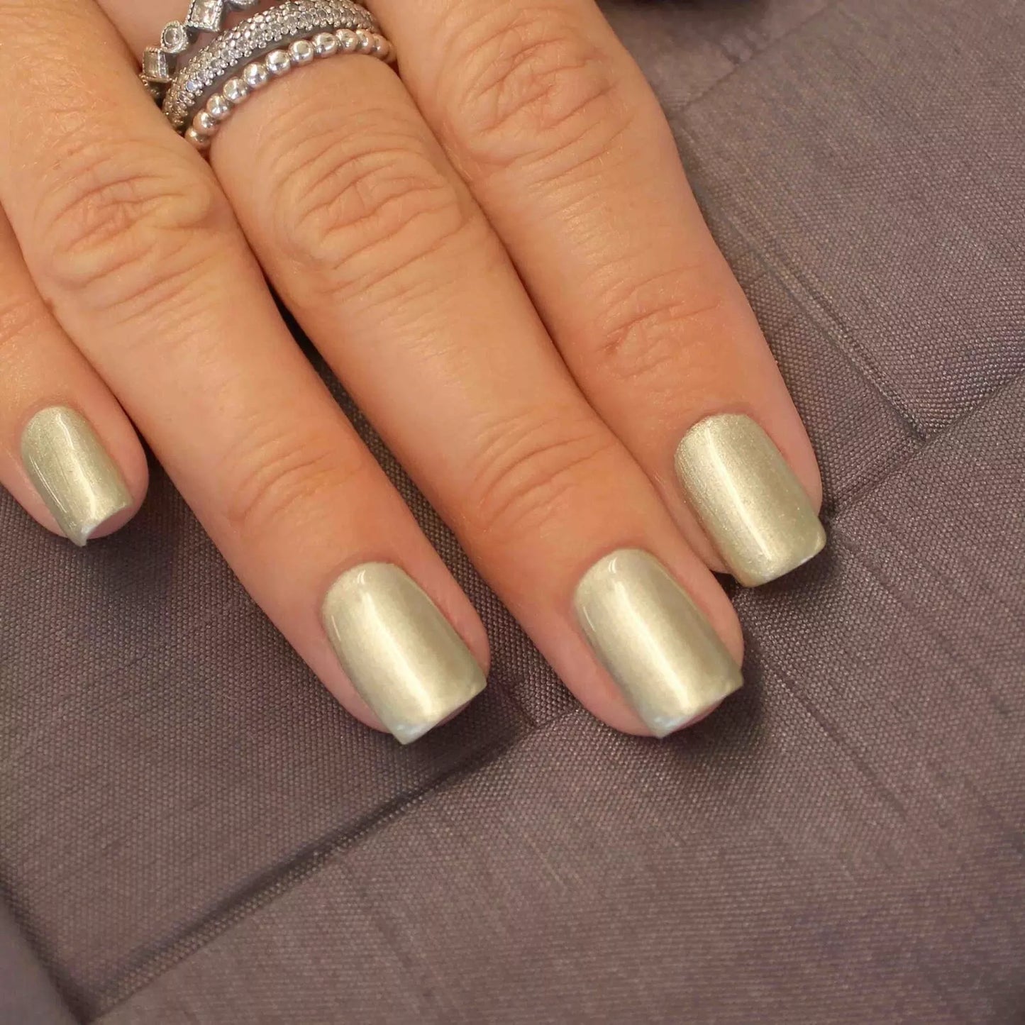 Hand wearing Bio Sculpture Gemini Nail Polish No. 251 Angelic Statue – bold, vegan pearlescent champagne polish for inclusive, radiant manicures