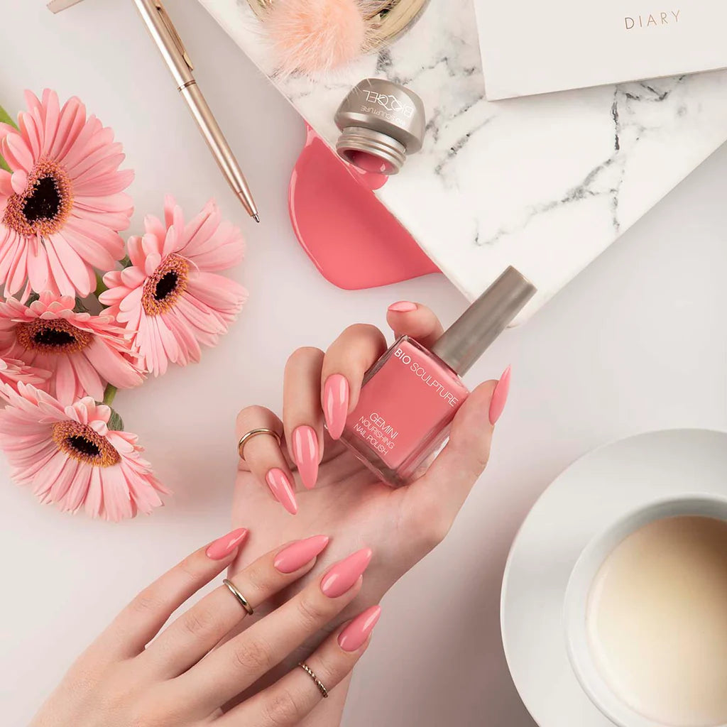 Hand with Bio Sculpture Gemini Nail Polish No. 273 Crazy Daisy nail polish bottle – soft pink coral vegan polish for a chic, contemporary manicure