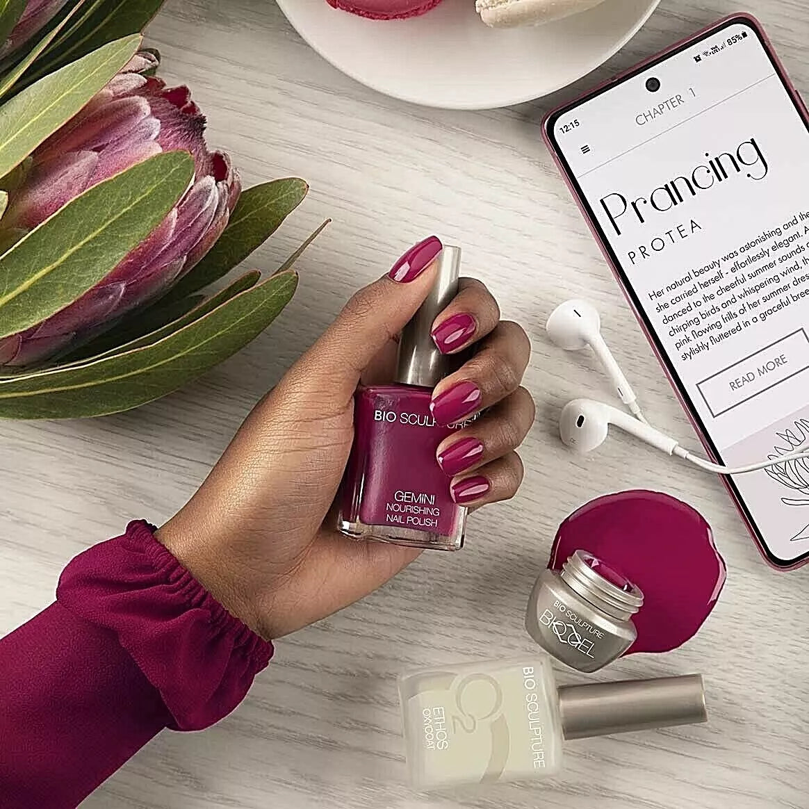 Hand holding Bio Sculpture Gemini Nail Polish No. 275 Prancing Protea nail polish – vegan, deep cherry red polish bottle for stylish, bold nails