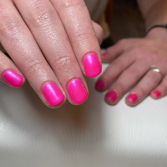 Hand wearing Bio Sculpture Gemini Nail Polish No. 102 Neon Pomegranate Ice – vegan, fluorescent pink polish with a purple sheen for a vibrant, statement nail look