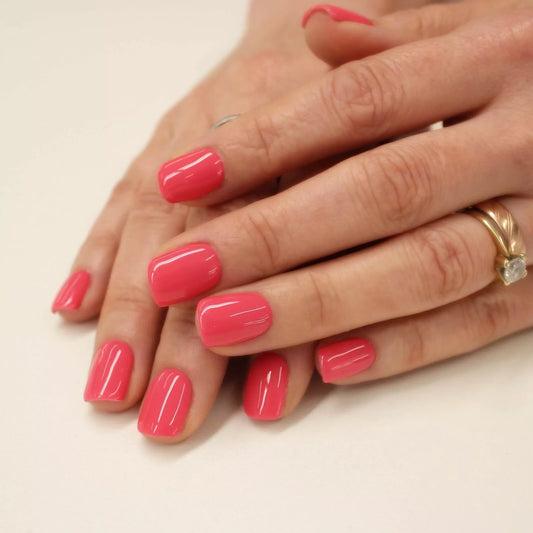 Hand wearing Bio Sculpture Gemini Nail Polish No. 250 Radiant Starfish – vegan, warm pink coral polish for a chic, radiant nail look