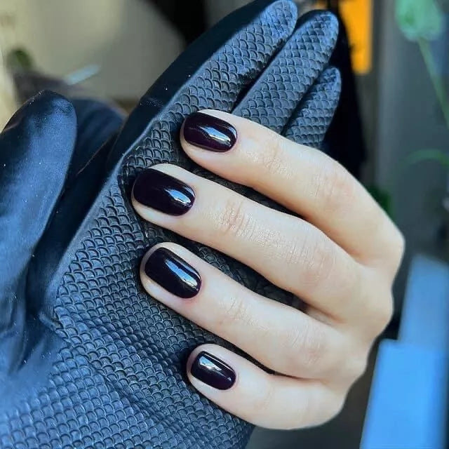 Hand with dark skin tone wearing Bio Sculpture Gemini Nail Polish No. 255 Knights Armour – bold, vegan deep dark violet polish for inclusive, striking manicures