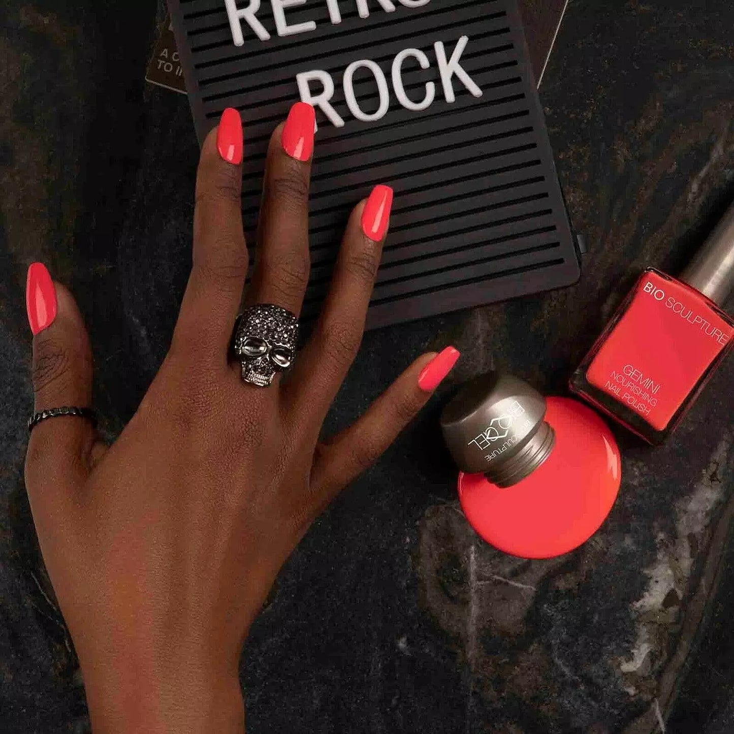 Hand with dark skin tone wearing Bio Sculpture Polish No. 284, Retro Rock – vivid, vegan berry red polish for inclusive, radiant manicures