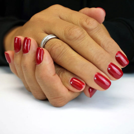 Hand wearing Bio Sculpture Gemini Nail Polish No. 30 Triginta – vegan, deep red polish for a chic, contemporary take on classic red nails