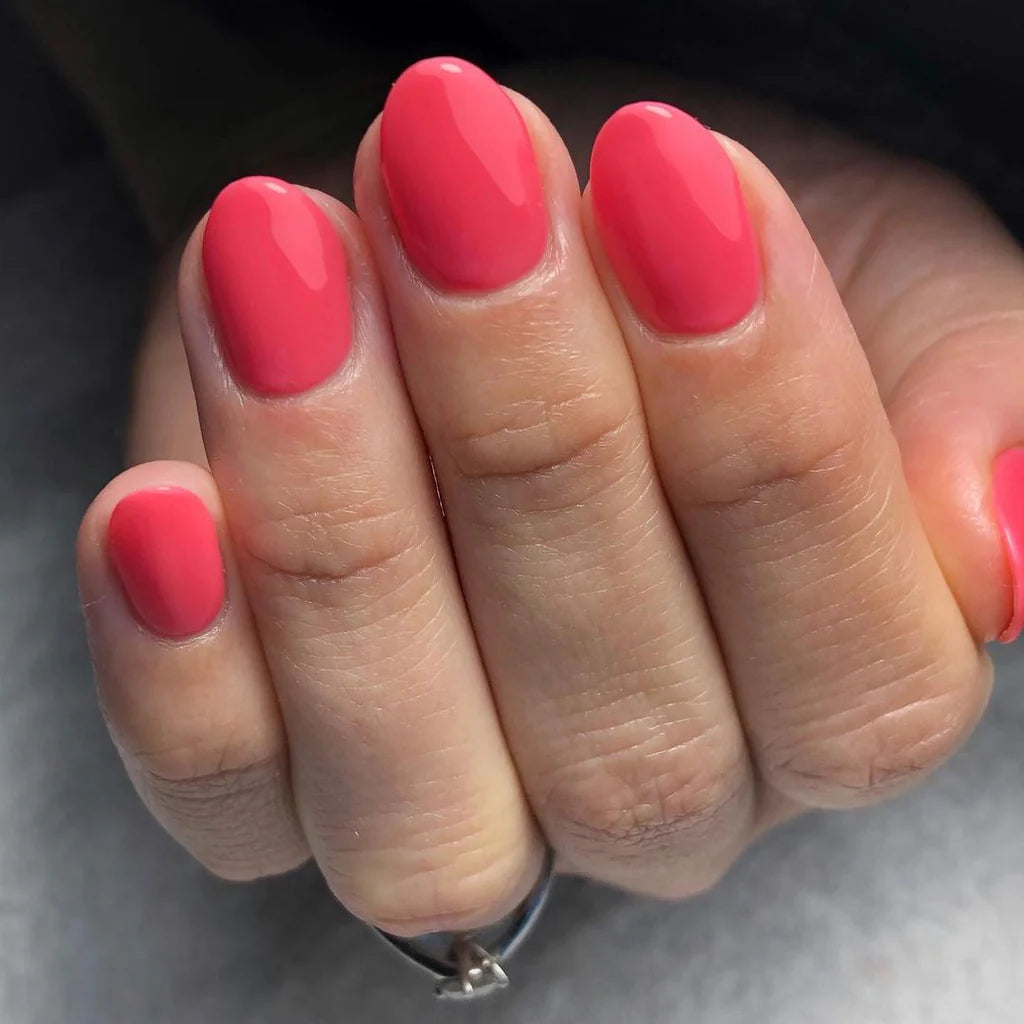 Hand with medium skin tone wearing Bio Sculpture Gemini Nail Polish No. 75 Fruity Tooty – vegan, vibrant coral pink polish for a fresh, radiant manicure