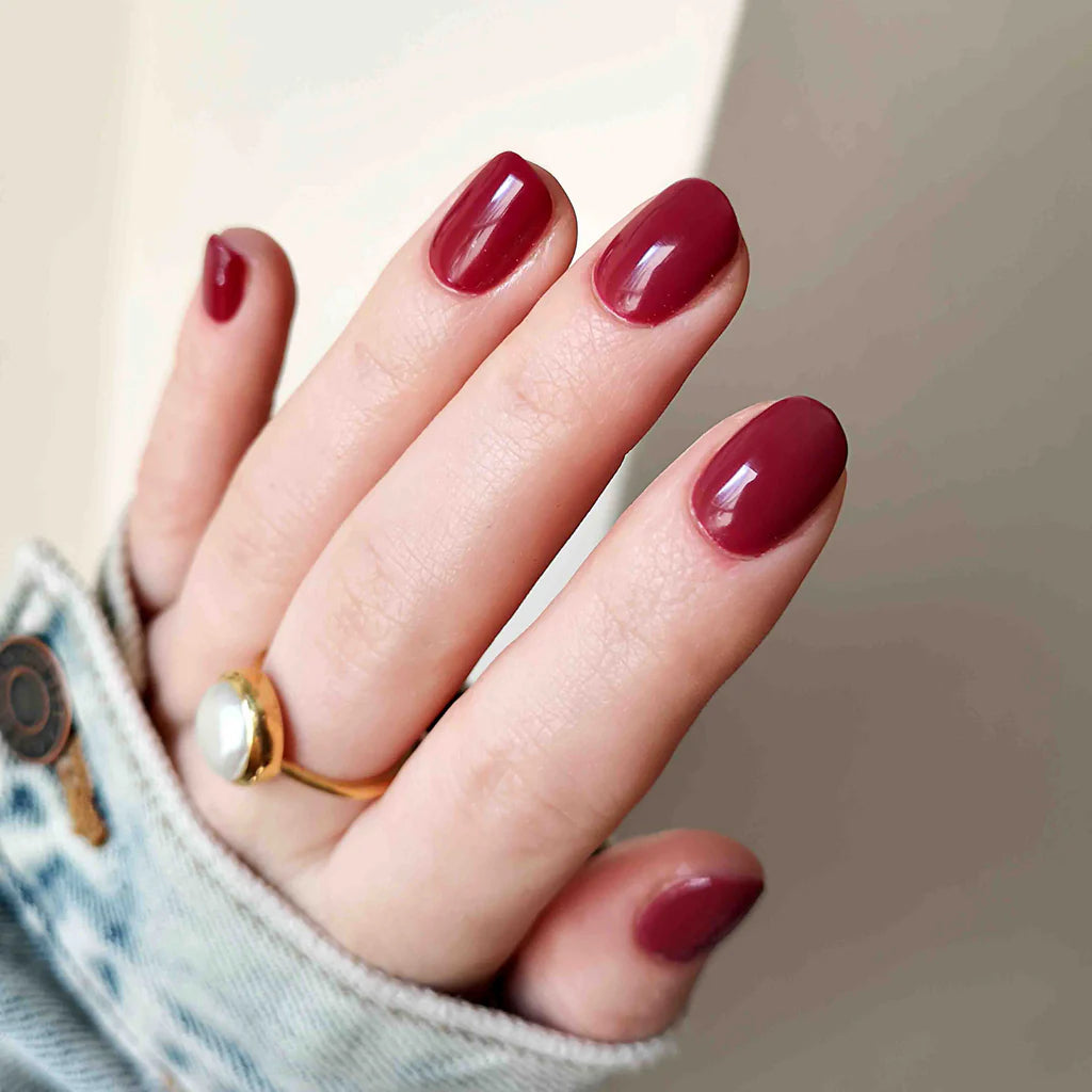 Fingers painted with Bio Sculpture Gemini Nail Polish No. 85 Mulberry on light skin – breathable, creamy mulberry polish for a polished, statement style