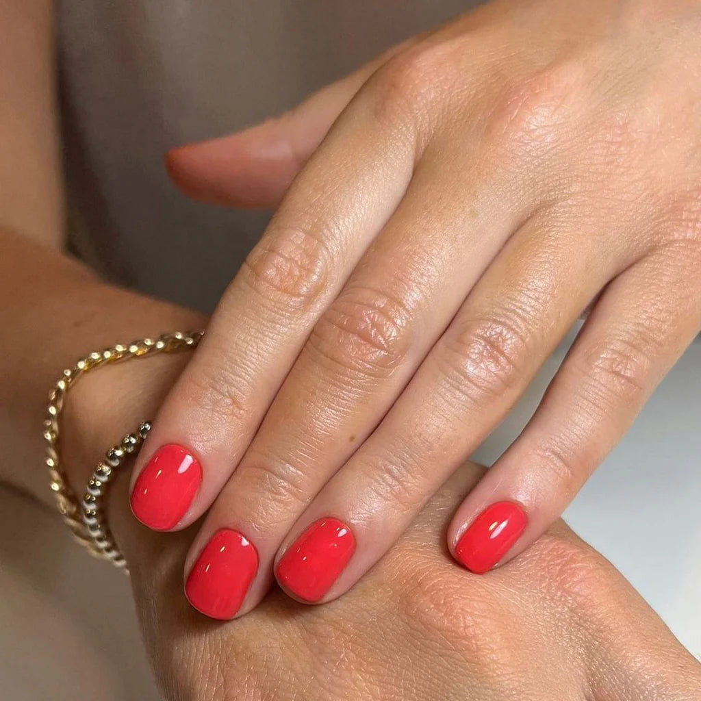 Hand wearing Bio Sculpture Gemini Nail Polish No. 95 Spring Splash – vegan, bright orange coral polish for a fresh, radiant manicure