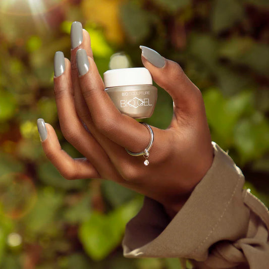 Hand with dark skin tone wearing Bio Sculpture Gemini Nail Polish No. 267 Ornamented Arch – vegan, muted mauve-brown polish for an inclusive, refined manicure