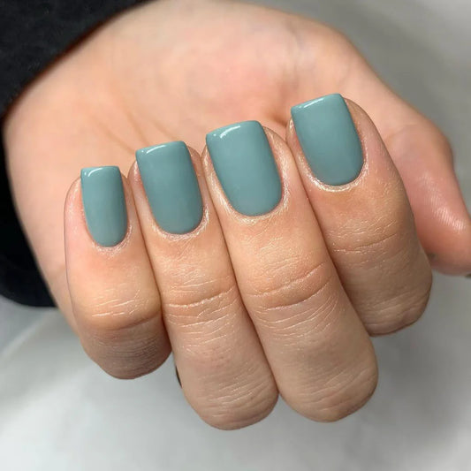 Hand wearing Bio Sculpture Gemini Nail Polish No. 262 Olive Poem – vegan, creamy olive-green polish for a chic, nature-inspired manicure inspired by Lydia Millin’s Evergreen Book