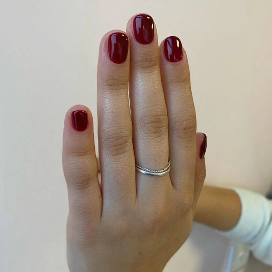 Hand wearing Bio Sculpture Gemini Nail Polish No. 24 Port Wine – vegan, deep red wine polish for a chic, sophisticated nail look