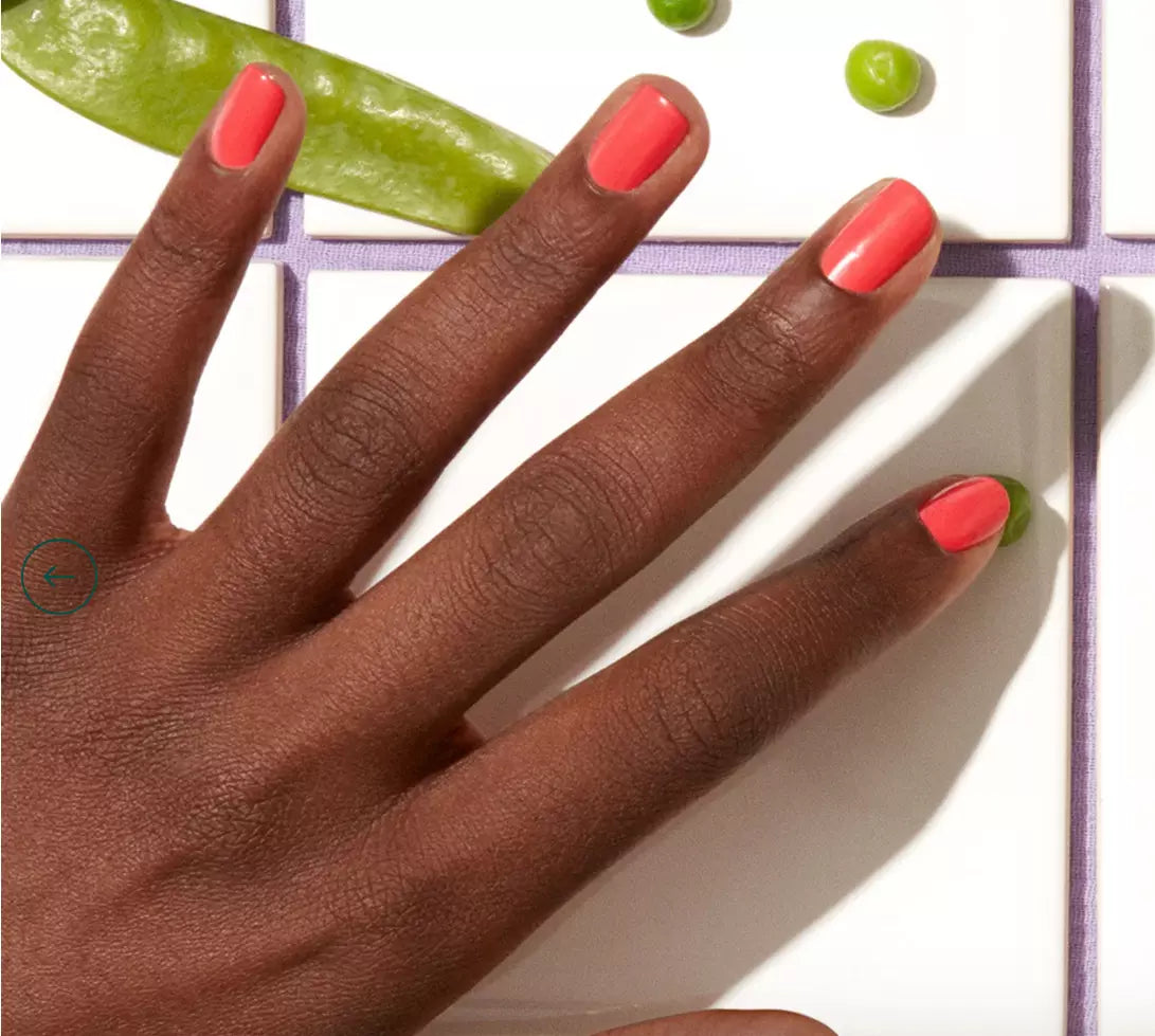 Fingers painted with Manucurist Pulp on darker skin – non-toxic, vibrant coral polish for modern style