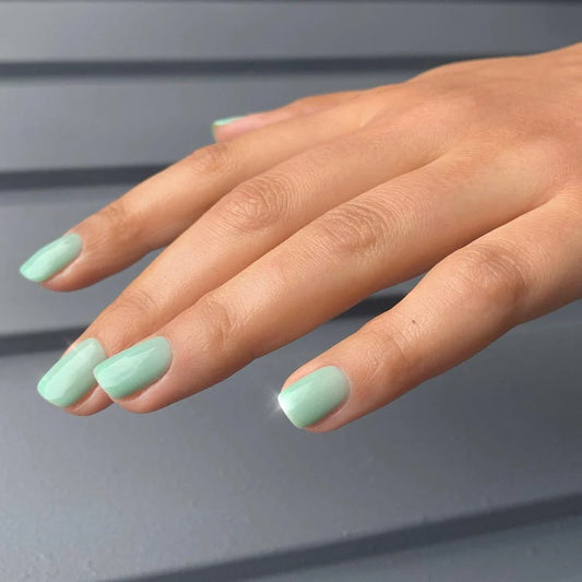 Hand wearing Bio Sculpture Gemini Nail Polish No. 100 Pistachio Green – vegan, light pastel green polish inspired by Lydia Millin Evergreen for a chic, modern nail look