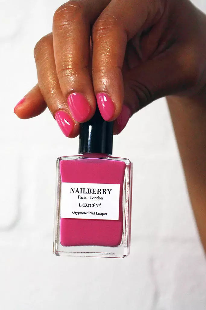 Hand holding Nailberry Pomegranate Juice nail polish – vibrant, vegan pomegranate red polish bottle for bold, healthy manicure