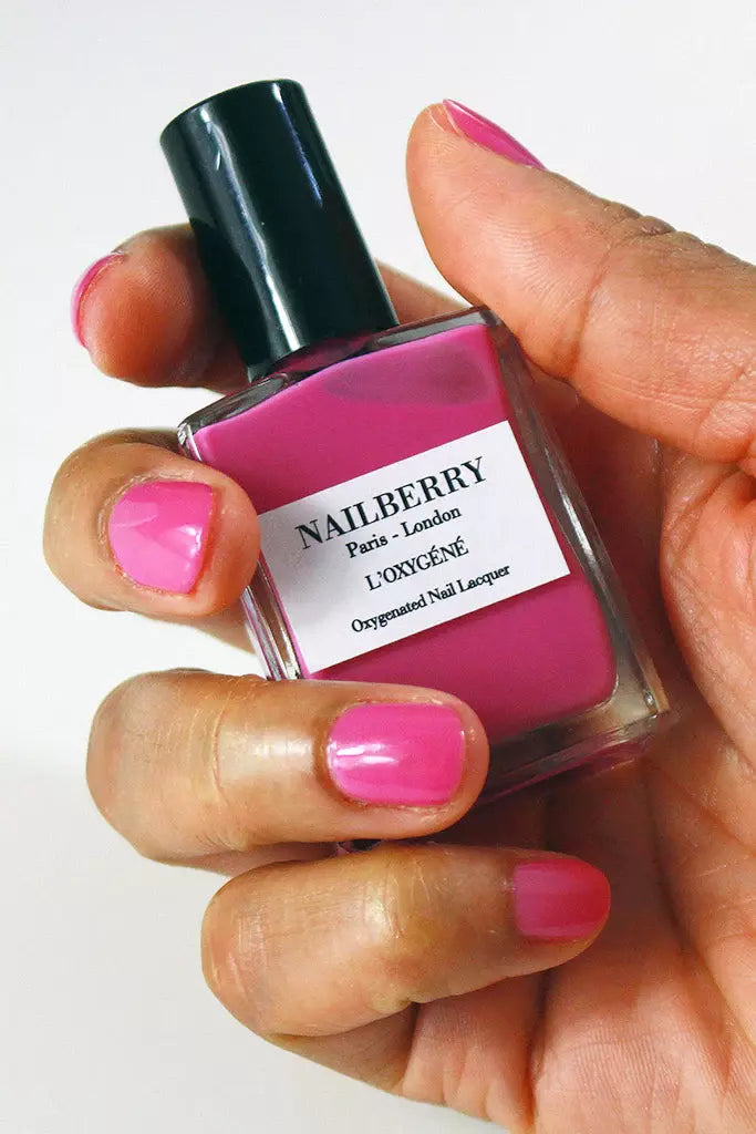 Hand holding Nailberry Pomegranate Juice nail polish – deep, vegan pomegranate red polish bottle for bold, elegant manicures