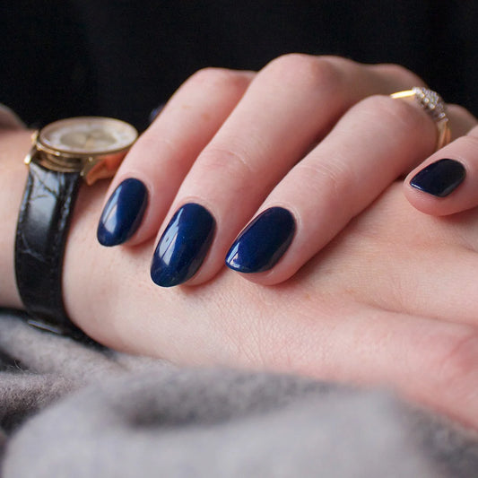 Hand wearing Bio Sculpture Gemini Nail Polish No. 264 Sapphire Song – vegan, deep sapphire blue polish for a chic, sophisticated nail look