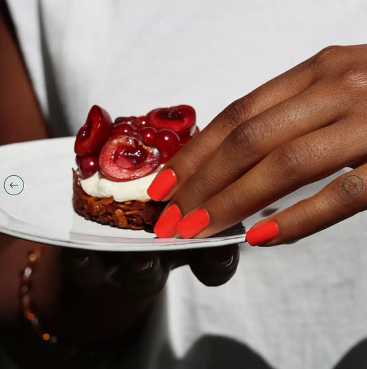 Close-up of Manucurist Paris Red Coral – bright, non-toxic coral red polish on nails for a bold summer look